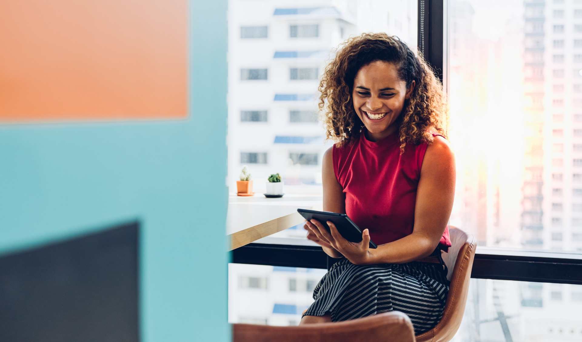 A woman smiling while working in an office on a tablet device